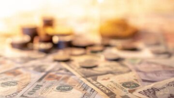 صورة توضح مجموعة من النقود الورقية والعملات المعدنية، تشمل فئات مختلفة من العملات. الخلفية غير واضحة، مما يبرز تفاصيل الأموال.
