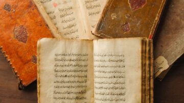 مجموعة من الكتب القديمة المفتوحة والمغلقة، تحتوي على نصوص مكتوبة بخط اليد. تظهر الصفحات الداخلية تفاصيل دقيقة من الخط العربي، مع تصاميم جلدية ملونة على الأغلفة. تعكس الصورة جمال التراث الأدبي والثقافي.