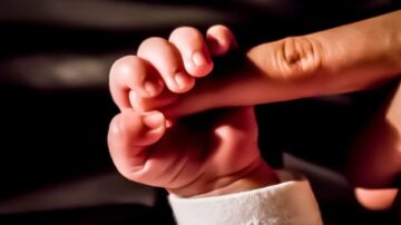 صورة تُظهر يد طفل صغيرة تمسك بإصبع شخص بالغ، مع التركيز على التفاصيل الدقيقة للأصابع والظلال. تعكس الصورة لحظة حميمية وتعزز الروابط الأسرية.