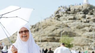 امرأة مسلمة في موسم الحج تحمل مظلة للوقاية من اشعة الشمس