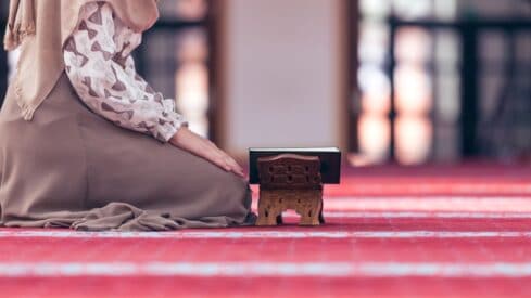امرأة تقرأ القران في المسجد والمصحف على الحامل