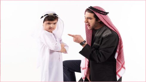 شخص بزي عربي يوجه اللوم الى طفل صغير برتدي زي عربي خليجي