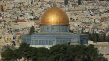 قبة الصخرة في القدس، مع قبة ذهبية لامعة، محاطة بمباني المدينة القديمة. تعتبر المعلم الديني والتاريخي بارزًا في الأفق.