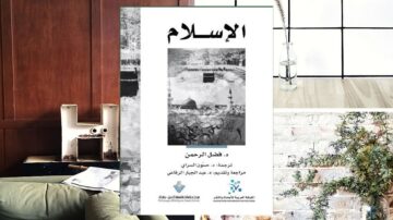 كتاب عن الإسلام مع غلاف باللون الأبيض والأسود يتضمن صورة لمدينة مقدسة، موضوع على طاولة بجانب جدار من الطوب. تظهر خلفية حديثة مع عناصر ديكور بسيطة.