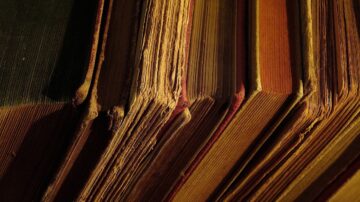 كتب قديمة بألوان دافئة، تظهر حواف الصفحات المتآكلة. تُبرز الصورة تفاصيل اللمسة الفنية للكتب، مما يعكس تاريخها وجمالها. مثالية لعشاق الأدب والتراث الثقافي.