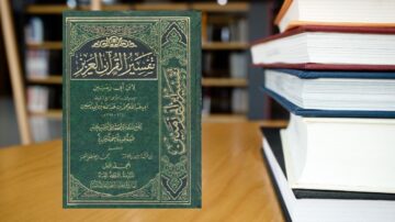 كتاب تفسير القرآن الكريم ذو غلاف أخضر مزخرف، موضوع على طاولة خشبية، مع كتب أخرى مكدسة في الخلفية، يجسد أهمية الدراسة الدينية والتراث الثقافي.