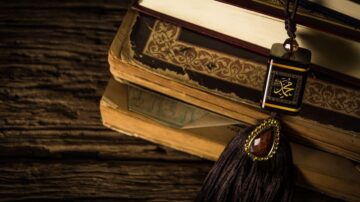 كتاب قديم مكدس مع تعليقة مزخرفة تحمل رموزًا صينية، تظهر تفاصيل دقيقة على الغلاف والخشب الداكن.