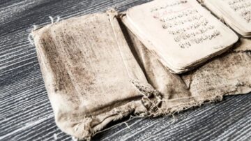 كتب قديمة مغطاة بالغبار، مع صفحات ممزقة ومخطوطة بخط عربي، تعكس تاريخ المعرفة والتراث الثقافي.