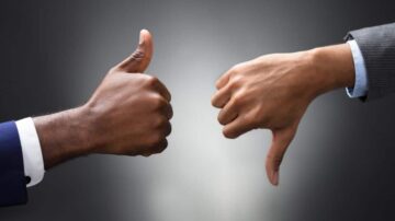 يد تظهر إبهامًا مرفوعًا وأخرى إبهامًا مائلًا لأسفل، على خلفية رمادية، تعبر عن تقييم إيجابي وسلبي.