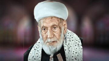 رجل مسن ذو لحية بيضاء وشعر أبيض يرتدي عمامة وملابس تقليدية، يظهر في خلفية ناعمة غير واضحة، تعكس أجواء تاريخية وثقافية.