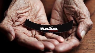 يدين مسنّتين تحملان شعار "حكمة" باللونين الأبيض والأسود، مع خلفية خشبية. تعكس الصورة مفهوم الحكمة والتجارب الحياتية.