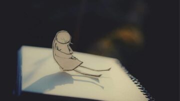 رسمة بسيطة لشخصية ورقية تجلس على دفتر ملاحظات، تعكس شعور الحزن والانعزال، مع تأثيرات الإضاءة الناعمة التي تضيف عمقًا للصورة.