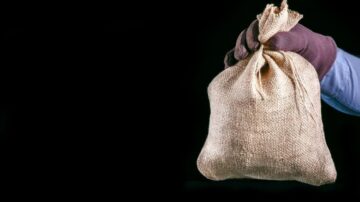 كيس من القماش الخشن محمول بيد يرتدي قفازًا. الخلفية سوداء، مما يبرز تفاصيل الكيس.