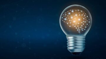 مصباح كهربائي يحتوي على رسم بياني يمثل الدماغ، مع شبكة من النقاط المتصلة تضيء بلون برتقالي على خلفية زرقاء داكنة. تعبير عن الابتكار والأفكار.