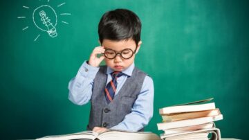 طفل يرتدي نظارات وقميصًا أنيقًا يقف أمام لوح أخضر، يقرأ كتابًا بتركيز. بجانبه، توجد مجموعة من الكتب. فوق رأسه، يوجد رسم توضيحي لمصباح، مما يدل على فكرة أو إلهام.