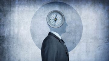 شخص يرتدي بدلة، ورأسه عبارة عن بوصلة، خلفية رمادية، تعبير عن التوجيه والقرارات.