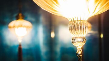 مصابيح زجاجية أنيقة تتألق بإضاءة دافئة، مع خلفية زرقاء ناعمة. تصميم فني يعكس الفخامة والجمال، مثالي لتزيين المساحات الداخلية.