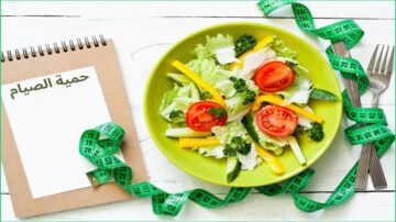 سلطة خضار طازجة في طبق أخضر مع طماطم، فلفل أصفر، وخس، محاطة بشريط قياس. خلفية بيضاء مع ورقة فارغة. تعكس الصورة مفهوم الحمية الصحية.