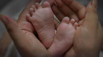 أقدام رضيع صغيرة في يدين كبيرتين، تعبير عن الحب والرعاية. الصورة تعكس براءة الطفولة والحنان.