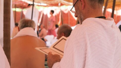 مسلم بملابس الإحرام اثناء فريضة الحاج يقرأ القرأن