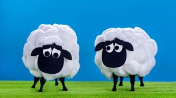 خروفان مصنوعيان مصنوعان من القطن، مع عيون كبيرة وأوجه حزينة، يقفان على خلفية زرقاء، في منظر طبيعي أخضر.