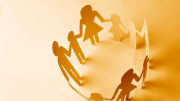 صورة تمثل أشخاصًا مصنوعة من ورق ملون، متشابكين بأيديهم في دائرة. الخلفية بلون برتقالي فاتح، مما يبرز الروابط الأسرية والتواصل الاجتماعي.