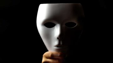 قناع أبيض يحمل بيد واحدة، خلفية داكنة، يبرز تفاصيل الوجه بشكل غامض. يرمز إلى الهوية والتغيير.