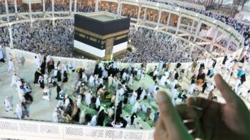 مشهد لزوار الكعبة في مكة المكرمة، يظهر الحشود الكبيرة حول الكعبة المشرفة مع أداء الطواف، وتفاصيل المعمار المحيط بالمكان.