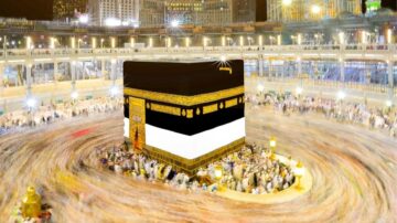 الكعبة المشرفة في مكة المكرمة، محاطة بالحجاج الذين يدورون حولها، مع إضاءة ساطعة تعكس روحانية المكان.