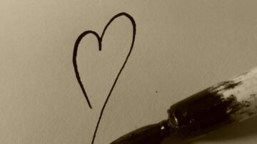 رسم قلب بسيط بخط أسود على ورقة، مع قلم تحديد بالقرب من الرسم.