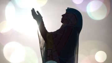 امرأة ترتدي حجابًا، ترفع يديها في دعاء، silhouetted against خلفية مضيئة مع دوائر ملونة. تعبر الصورة عن الروحانية والإيمان.
