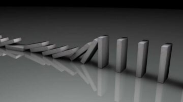 سلسلة من قطع الدومينو الرمادية تتساقط بشكل متتابع، مع انعكاسات واضحة على السطح اللامع. تُظهر الصورة تأثير الحركة المتتالية وكيف تؤثر قطعة واحدة على الأخرى.