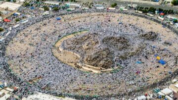 تجمع حجاج بيت الله الحرام حول جبل عرفات في مشهد يعكس روح العبادة والتواضع خلال موسم الحج. يظهر الحجاج بالملابس البيضاء في ساحة واسعة، مع وجود عدد كبير من الخيام والمرافق المحيطة.