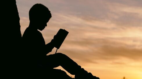 طفل يمسك كتاب ويقرأ