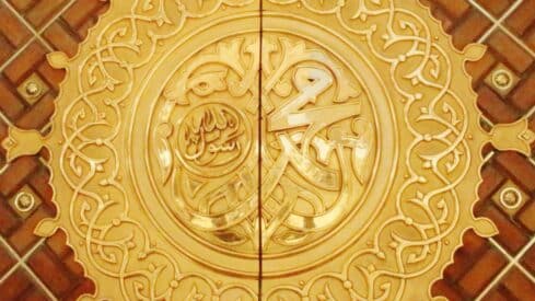 A circular gold engraving in the name of the Prophet Muhammad, may God bless him and grant him peace, decorated with fine details.