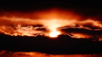 غروب شمس مشمس خلف سحب داكنة، يخلق تباينًا بين الألوان البرتقالية والسوداء، مما يضفي جوًا دراميًا على السماء.