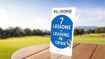 كتاب 7 دروس في القيادة خلال الأزمات لمؤلفه بيل جورج، موضوع على طاولة خشبية في بيئة خارجية خضراء مع منظر طبيعي جميل في الخلفية.