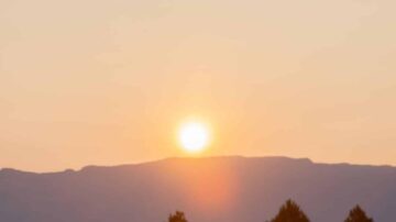 غروب الشمس فوق الجبال مع لون السماء الهادئ، يخلق مشهدًا طبيعيًا ساحرًا.