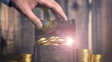 يد تظهر وهي تفتح صندوق كنز خشبي مليء بالعملات الذهبية اللامعة، مع وجود أكوام من العملات الذهبية بجانب الصندوق، وخلفية خشبية تعزز جو الاكتشاف والثروة.