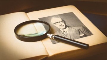 صورة لكتاب مفتوح يظهر صورة شخصية في الصفحة الوسطى، مع عدسة مكبرة موضوعة فوق الصورة. الخلفية ضبابية قليلاً، مما يبرز الكتاب والصورة.