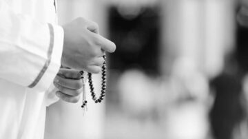 رجل يحمل سبحة في يده، يرتدي ثوباً تقليدياً، الخلفية ضبابية تعكس أجواء روحية. تمثل الصورة لحظة تأمل وصلاة، مما يعكس أهمية العبادة في الثقافة.