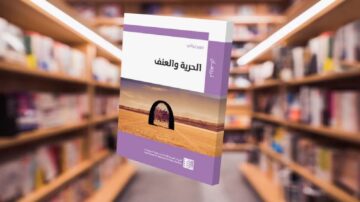 كتاب "الحرية والعنف" مع غلاف يظهر مشهداً طبيعياً، معروض في مكتبة تحتوي على رفوف مليئة بالكتب.