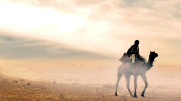 راكب جمل يسير عبر صحراء شاسعة تحت سماء غائمة، مع غبار يتصاعد في الهواء.