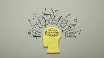صورة توضح رأسًا بشريًا مصنوعًا من ورقة صفراء، مع رسومات توضيحية لأفكار وأسئلة تتصاعد من الرأس، تعبر عن التفكير والفضول.