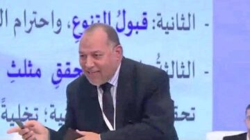 رجل يتحدث في مؤتمر، يعبر عن أفكاره بوضوح. خلفه نص عربي يبرز موضوعات متعددة مثل قبول التنوع واحترام الاختلاف.