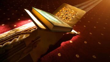 كتاب مفتوح على حامل خشبي، موضوع على سجادة حمراء مزخرفة. الضوء يتسلل بشكل دافئ على الكتاب، مع تصميم هندسي جميل على الحامل.