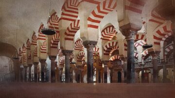 قوسات ملونة باللونين الأحمر والأبيض في مسجد تاريخي، مع أعمدة عالية وسقف مزخرف. تعكس الأضواء الخافتة جمال العمارة الإسلامية.