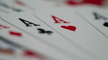 أوراق لعب تظهر مجموعة من الآسات، مع ورقة الآس القلبية مرئية بوضوح، خلفية ضبابية.