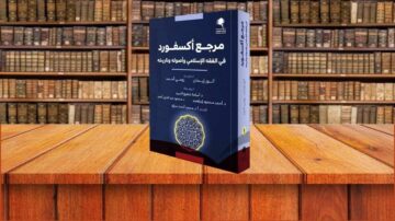 كتاب مرجع أكسفورد في اللغة الإسلامية وأصولها وتاريخها معروض على طاولة خشبية، خلفه مكتبة تحتوي على رفوف مليئة بالكتب القديمة.