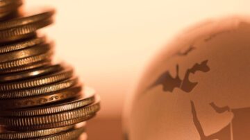 صورة توضح مجموعة من العملات المعدنية مكدسة بجانب كرة أرضية، مما يعكس مفهوم المال والاقتصاد العالمي.